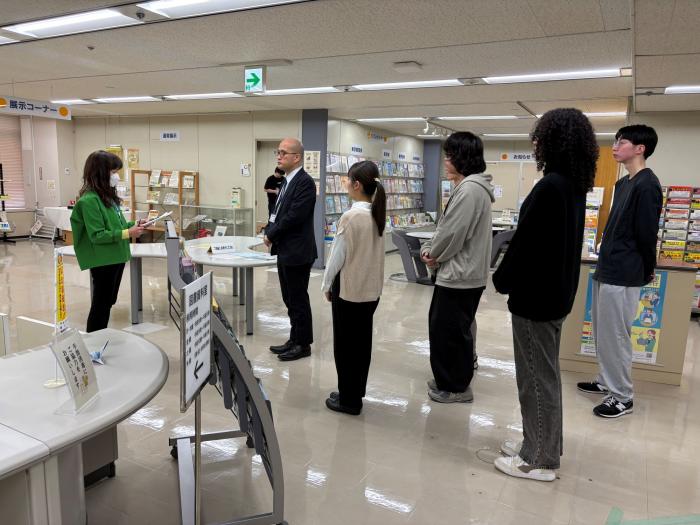 図書資料室の展示物を囲み、関係者が説明を受けている様子です。